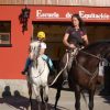Niña montando un pony blanco guiada por una instructora frente a la Escuela de Equitación en el Valle de Arán